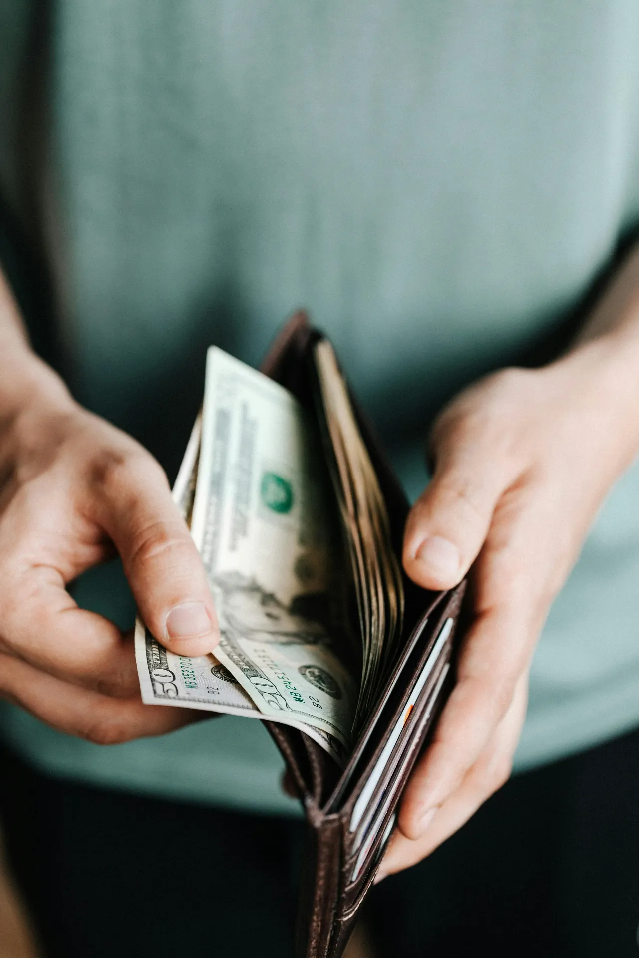 Man holding wallet with dollar out of his wallet