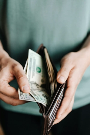 Man holding wallet with dollar out of his wallet